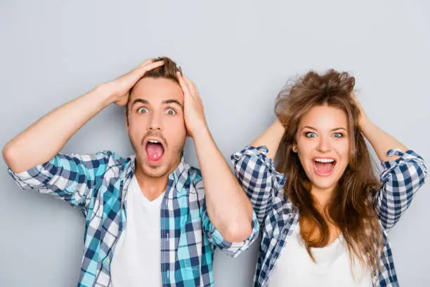 Photo of Portrait of surprised man and woman screaming and touching hair