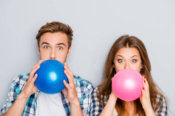 retrato de feliz joven hombre y mujer de inflar globos - balloon blowing inflating child fotografías e imágenes de stock