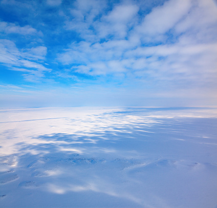 Aerial view above the snow-covered space of endless tundra in time of cloudy winter day.