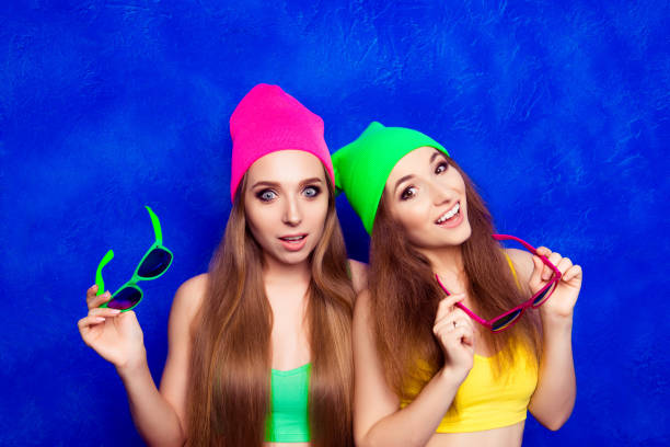 istock Happy girlfriends holding glasses standing near  blue wall 954107828