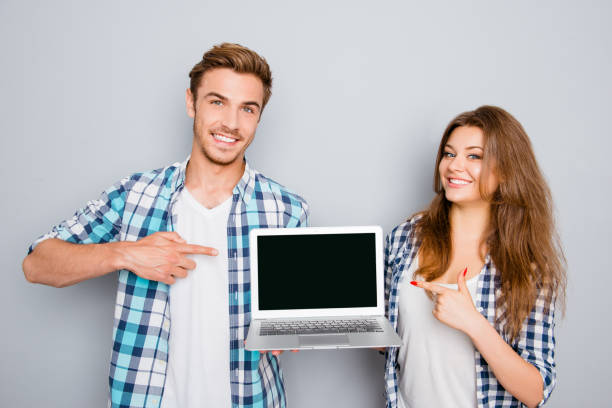istock Young couple demonstrating laptop and pointing on screen with copyspace 954109388
