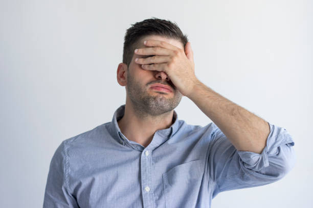 istock Exhausted young man with stubble covering face with hand 954111560