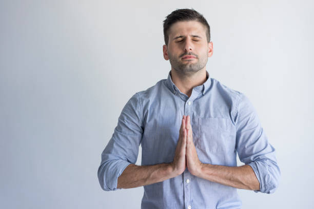 istock Peaceful young man with closed eyes touching hands together 954111610
