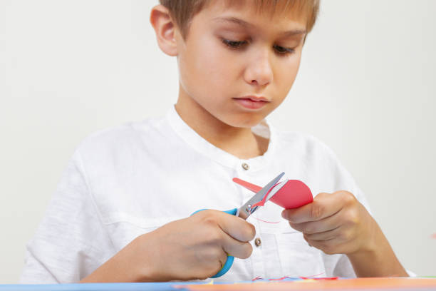 istock Child cutting red paper heart with scissors 954112468