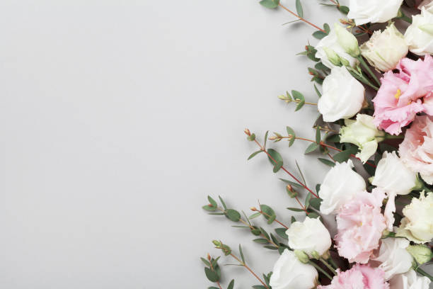 istock Fresh flowers and green eucalyptus leaves on gray table top view. Flat lay. 954120134