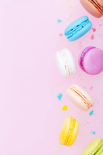 istock Falling cake macaron or macaroon on pink pastel background. Colorful almond cookies. 954121052