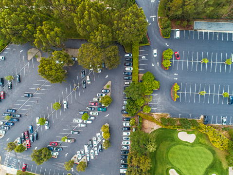 This picture shows that a aerial view of a parking area and golf course.The picture is taken from overhead.