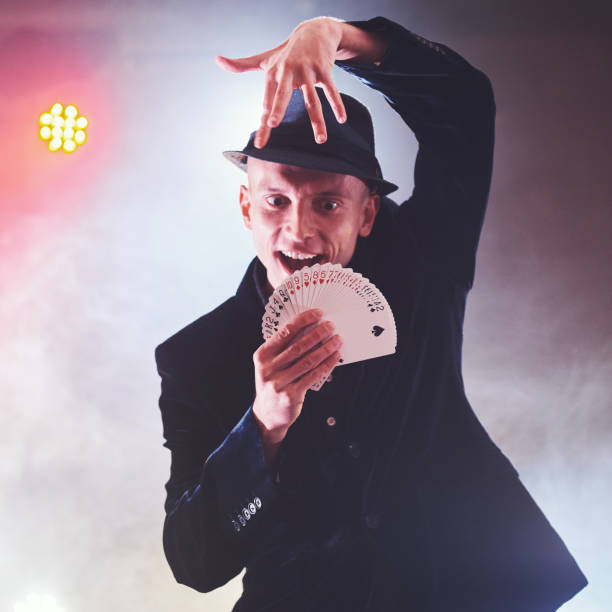 istock Magician showing trick with playing cards. Magic or dexterity, circus, gambling. Prestidigitator in dark room with fog 954125620