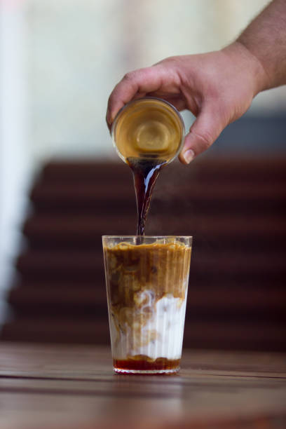 istock Man's hand pouring espresso to cold latte coffee 954141348