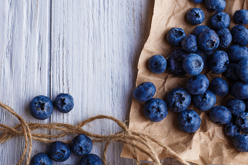 Blueberries on craft paper, close-up. Delicious berries on rustic wooden background
