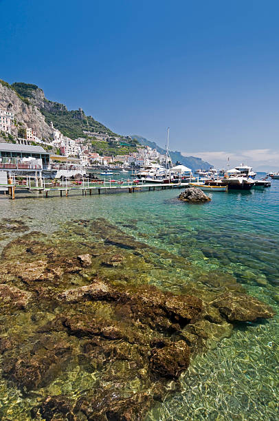 Amalfi, Italy - April 30, 2013: A SITA bus drives on the main coastal road towards the town of Amalfi. Several other cars and their registration plates are visible. 