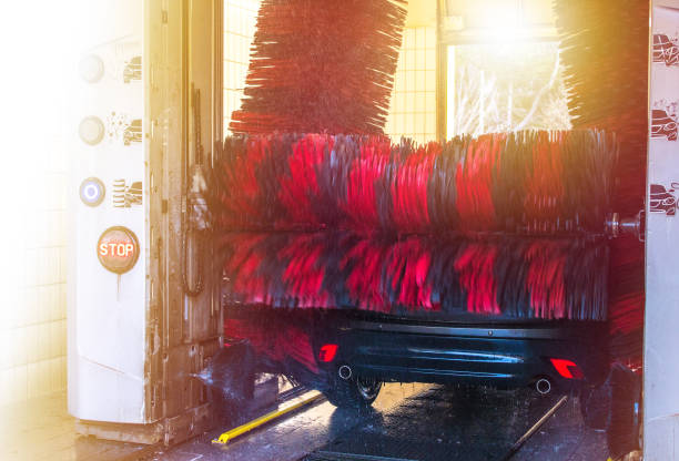 Car washing station with automatic rotating wash brushes in action. Automatic conveyorized tunnel car wash. View from inside