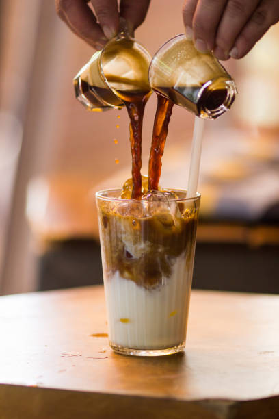 istock Man's hand pouring espresso to cold latte coffee 954142596