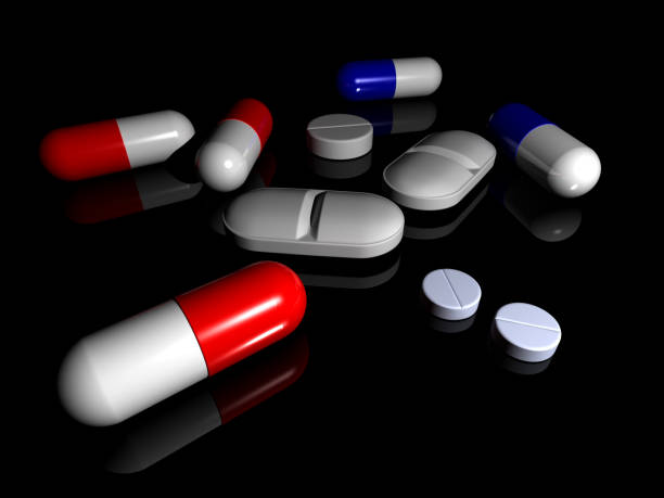 collection of pills on black reflective surface stock photo