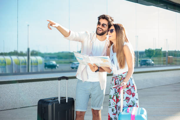 istock Two happy young tourists looking at the map and finding directions 954145230