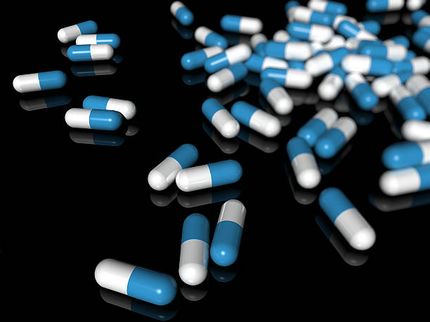 blue capsules on a black reflective surface stock photo