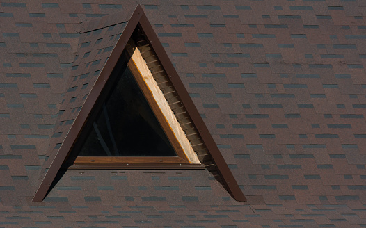 Attic triangular window on the roof in sunlight close-up