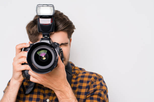 junger mann mit schwerpunkt mit digitalkamera isoliert auf weißem hintergrund - fotograf stock-fotos und bilder