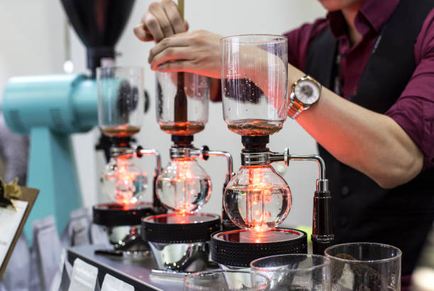 preparazione del caffè passo dopo passo. processo di estrazione. barista versa sifone nel pallone dal bollitore di acqua calda - siphon foto e immagini stock