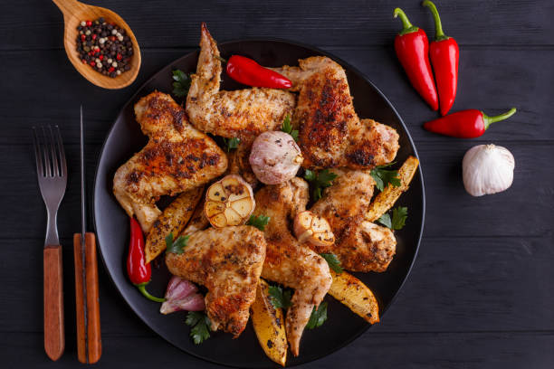 istock Grilled chicken wings on black  plate decorated with garlic and 954155920
