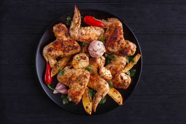 istock Grilled chicken wings with lemon and garlic on black plate. Cook 954155964