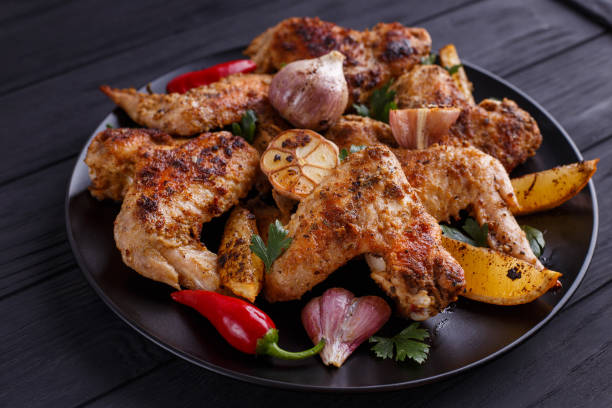 istock Grilled chicken wings on black plate decorated with garlic and s 954156892
