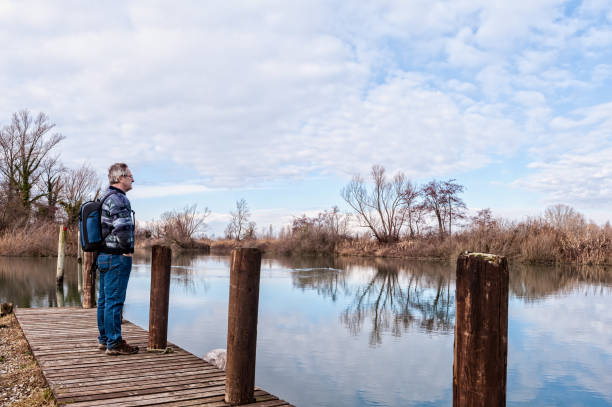istock Hiker with backpack over wood pier on shore of river. 954157888