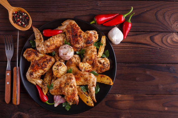 istock Grilled chicken wings on black plate decorated with garlic and s 954160970