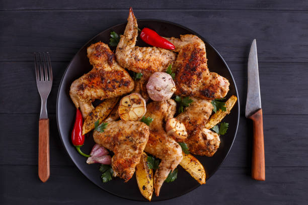istock Grilled chicken wings on black plate decorated with garlic, lemo 954162260