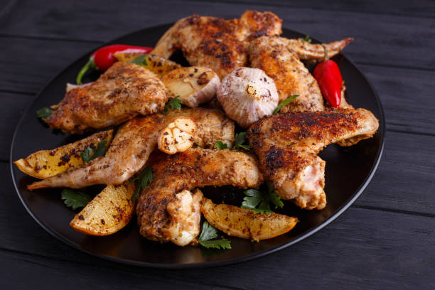 istock Grilled chicken wings on black plate decorated with garlic and s 954162280