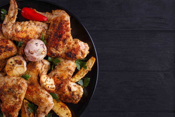 Grilled chicken wings on black plate decorated with garlic and s
