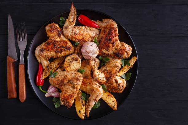 istock Grilled chicken wings on black plate decorated with garlic and s 954166742