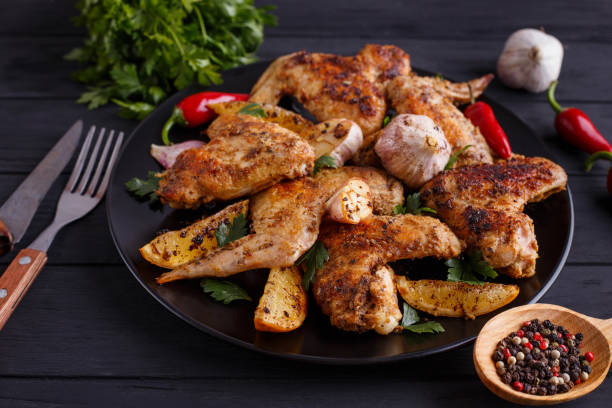 istock Grilled chicken wings on black plate decorated with garlic, lemo 954166808