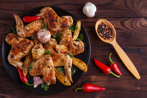 istock Grilled chicken wings on black plate decorated with garlic and s 954167694