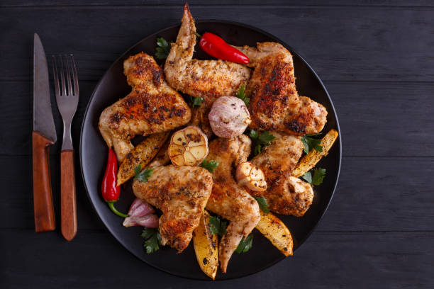 istock Grilled chicken wings on black plate decorated with garlic and s 954167730