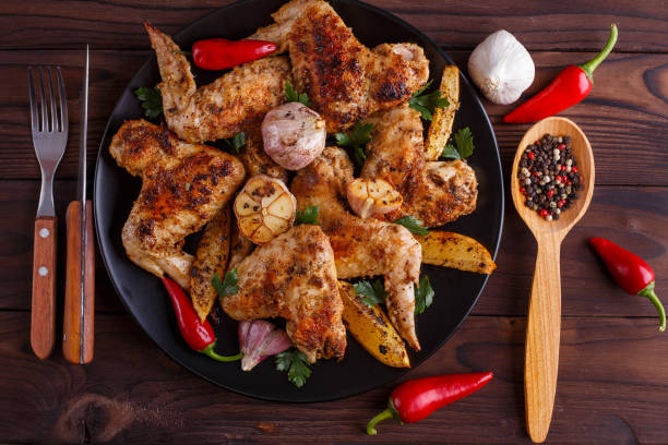 istock Grilled chicken wings on black plate decorated with garlic and s 954169000