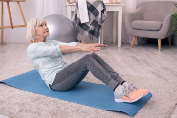 istock Fit elderly woman doing sit-ups at home 954171796
