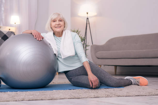 istock Cheerful elderly lady posing while leaning on yoga ball 954172932