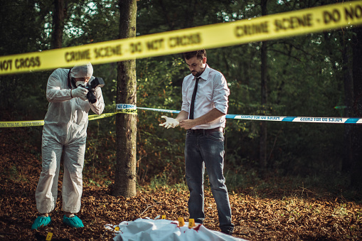 Detective and forensics on murder crime scene collecting evidence