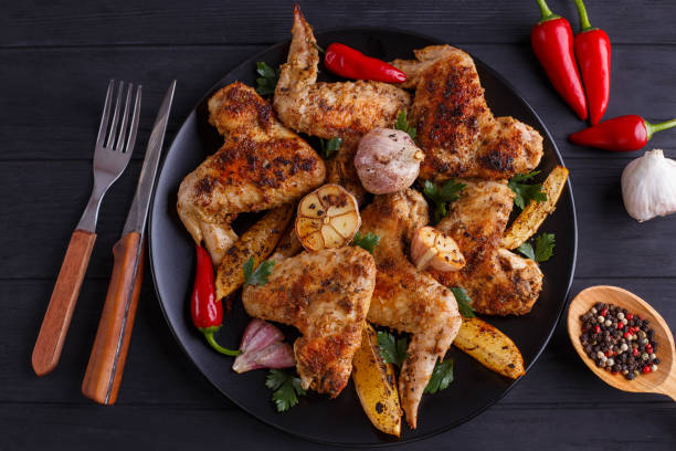 istock Grilled chicken wings on black plate decorated with garlic, lemo 954178352