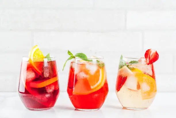 Cold white, pink and red sangria cocktails with fresh fruits, berries and mint.