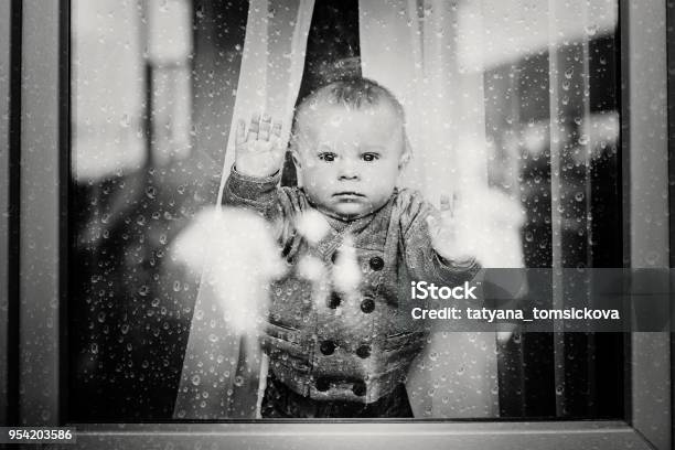 Cute Toddler Boy Staying At Home Behind The Glass Doors Watching Outside Stock Photo - Download Image Now