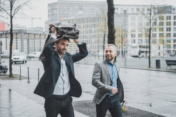istock Businessmen running with briefcases in the rain 954204262