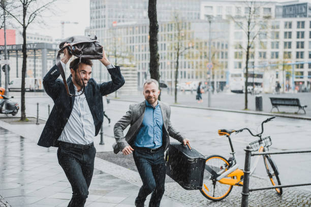 istock Businessmen running with briefcases in the rain 954204310