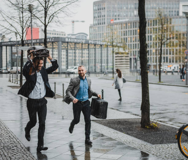 istock Businessmen running with briefcases in the rain 954204318