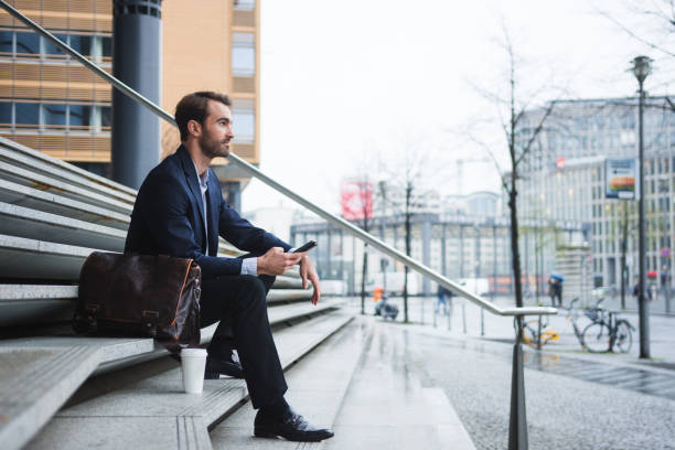 istock Businessman sitting on the stairs and using smart phone 954204326