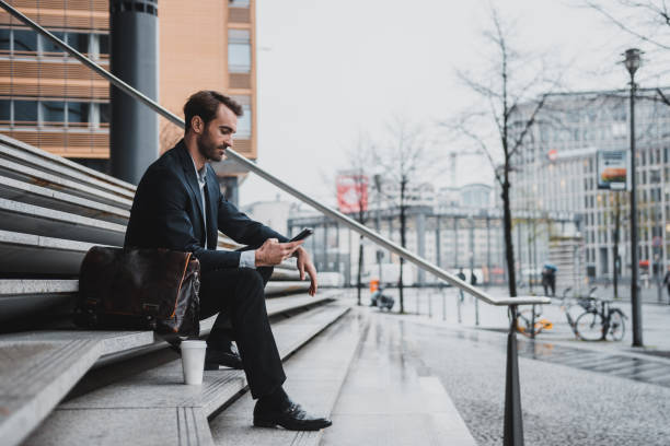 istock Businessman sitting on the stairs and using smart phone 954204370