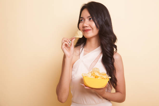 istock Young Asian woman eat potato chips. 954208930
