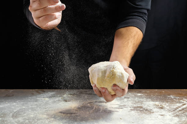 close-up de chef masculino mãos, sove a massa, cozinhe a massa em um fundo escuro. - bread kneading making human hand - fotografias e filmes do acervo