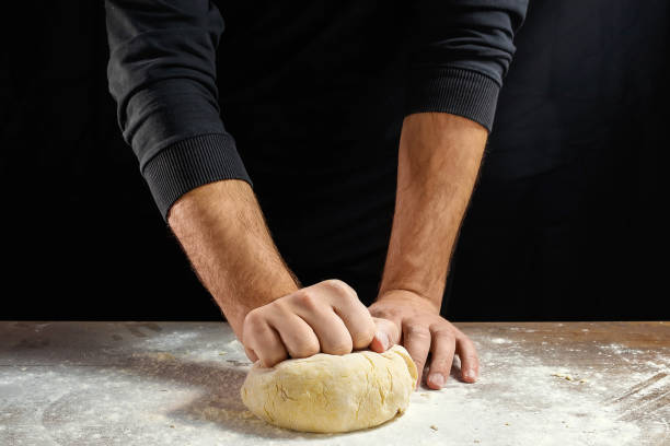 close-up de chef masculino mãos, sove a massa, cozinhe a massa em um fundo escuro. - bread kneading making human hand - fotografias e filmes do acervo